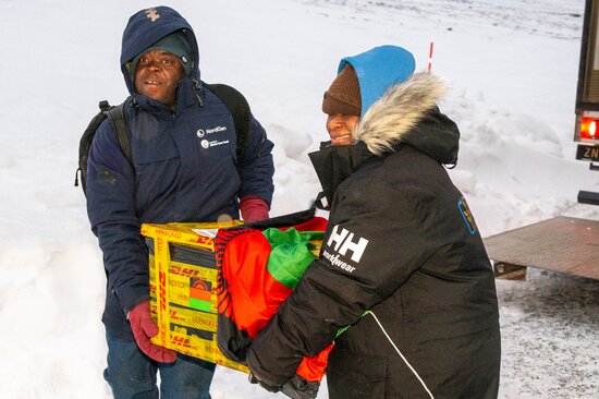 Patrick Kasasa (left) and a colleague share the load in carrying boxes of precious seeds to the entrance of the Svalbard Global Seed Vault. Photo: Mike Major/Crop Trust